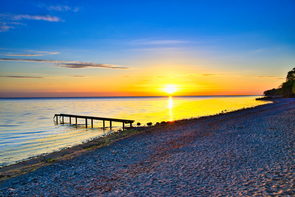 Farbenreicher Sonnenuntergang über der Ostsee am Timmendorfer Strand mit einem schmalen Holzsteg im Wasser.