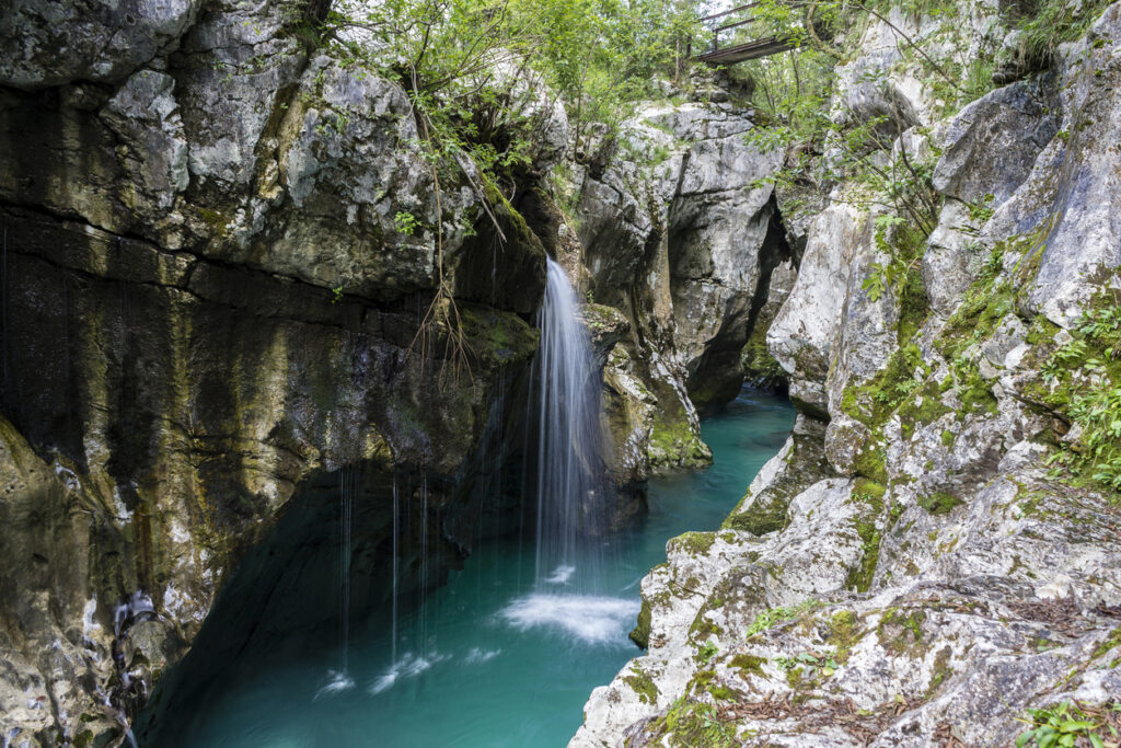 Kleiner Wasserfall stürzt in eine türkisgrüne Felsgumpen-Schlucht im Soča-Tal.
