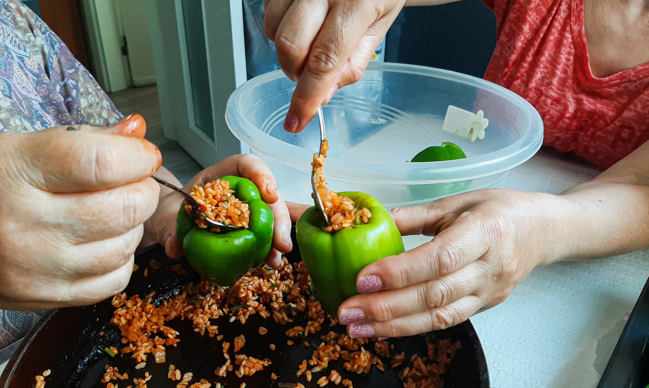 Zwei Frauen füllen grüne Paprikaschoten mit einer Reis-Füllung als ungarisches Gericht, gefüllte Paprikaschoten.