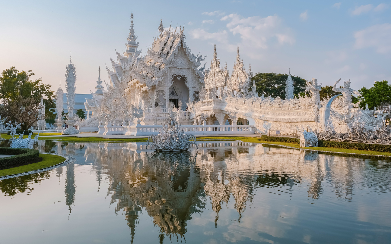 Der kunstvoll verzierte Wat Rong Khun in Chiang Rai spiegelt sich in einem Teich vor dem Tempel.