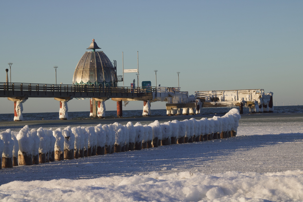 Verschneite Seebrücke mit Tauchgondel und vereisten Pfählen in Zingst im Winter an der Ostsee.