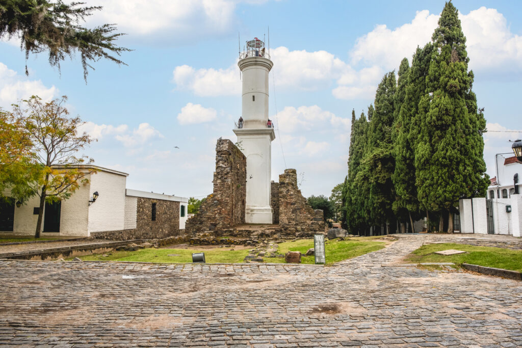Weißer Leuchtturm mit alten Steinruinen im historischen Zentrum von Colonia del Sacramento.