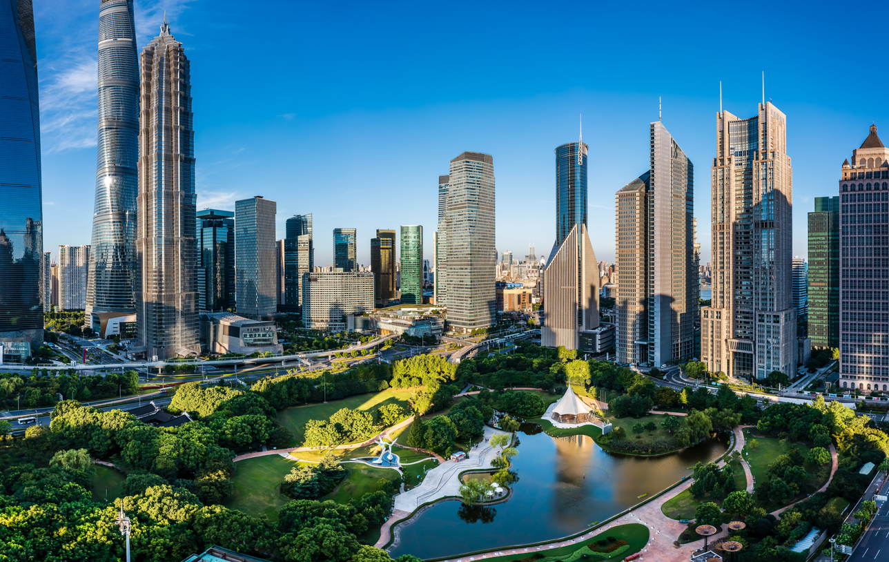 Panoramablick auf die Hochhäuser des Finanzviertels von Shanghai mit einem großen Stadtpark und Teich im Vordergrund.