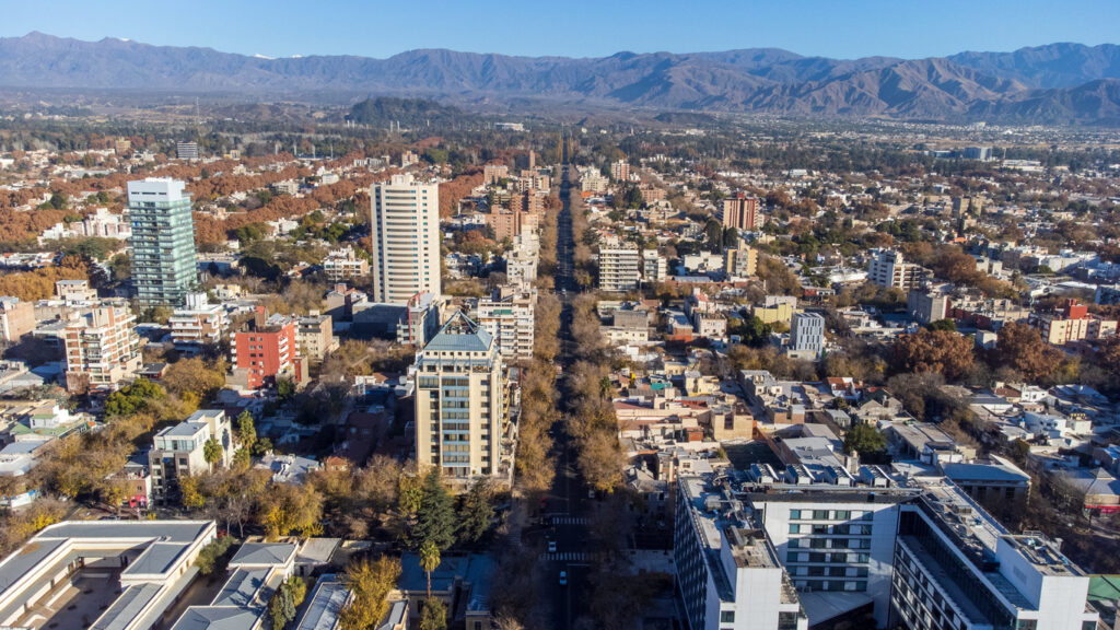 Luftaufnahme von Mendoza in Argentinien mit breiter, baumgesäumter Allee und den Anden im Hintergrund.