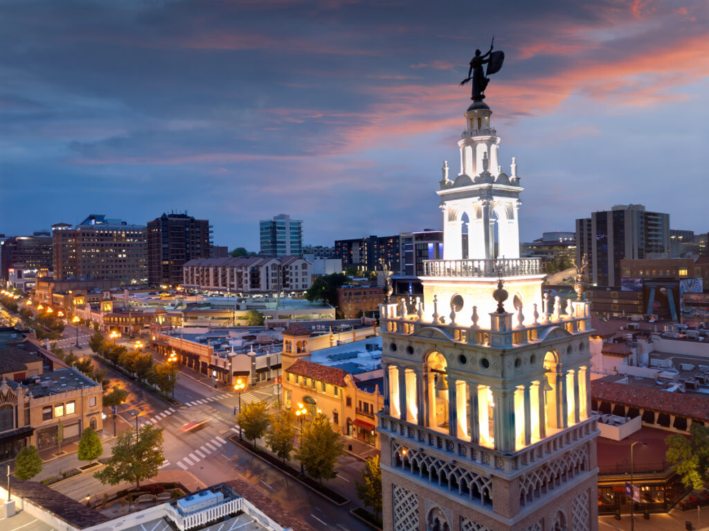 Erleuchteter Turm und Einkaufsviertel des Country Club Plaza in Kansas City bei Abenddämmerung.