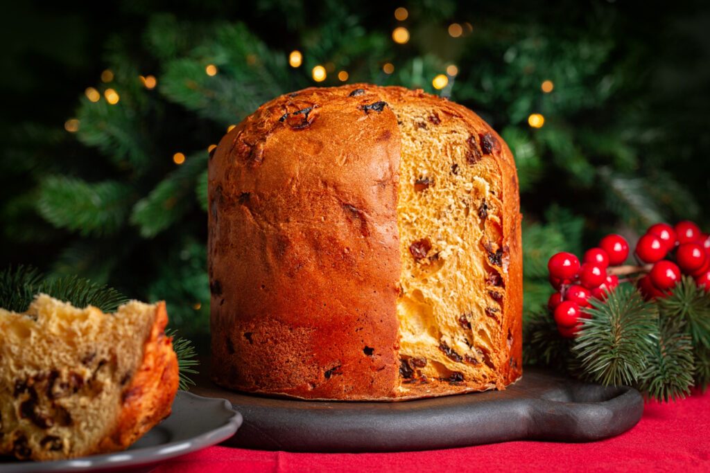 Ein angeschnittener Panettone steht festlich dekoriert auf einem Tisch.