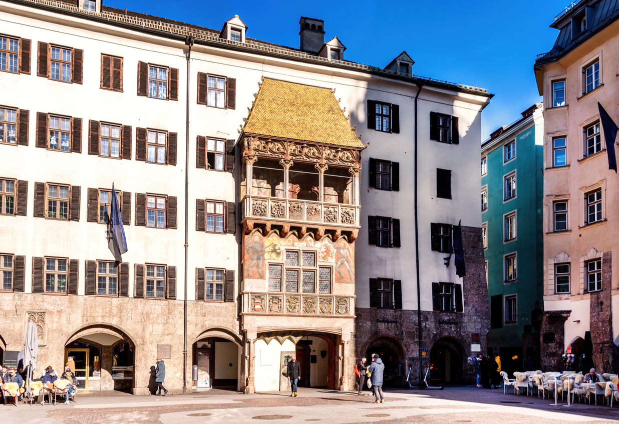 Das berühmte Goldene Dachl in Innsbruck leuchtet in der Sonne zwischen den historischen Fassaden.