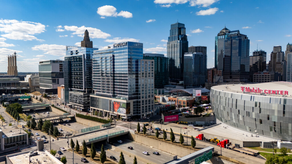 Hochhäuser und der T-Mobile Center in Kansas City bei Tag, davor Straßen und Verkehr.