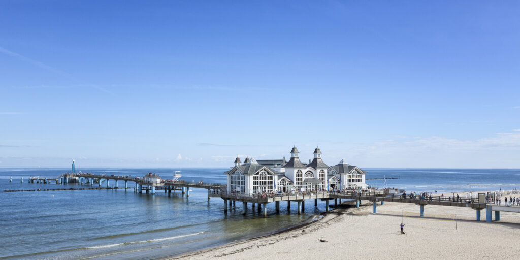 Die Seebrücke Sellin auf Rügen führt vom Strand zu einem weißen Brückenhaus über dem Wasser.