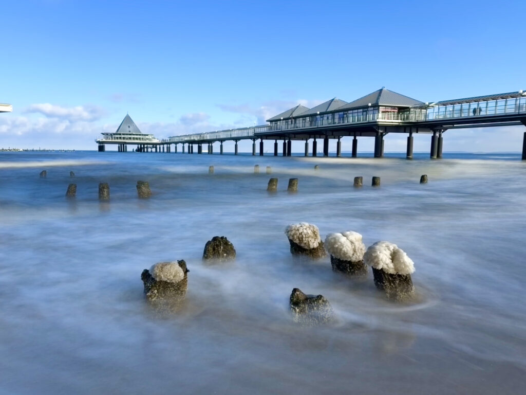 Die Seebrücke Heringsdorf ragt weit in die Ostsee, während das Wasser weich verschwimmt.