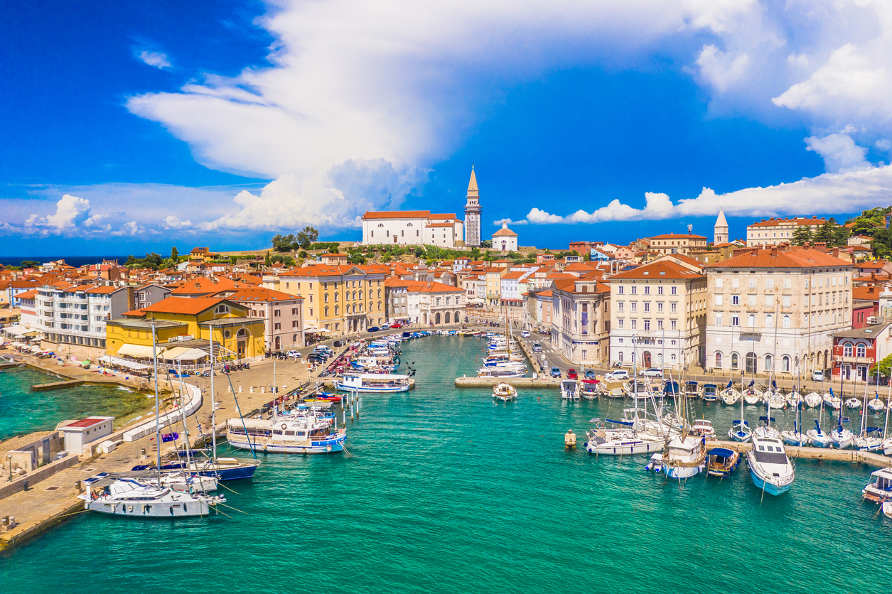 Segelboote und kleine Schiffe im Hafen von Piran in Slowenien vor den historischen Häusern der Altstadt.