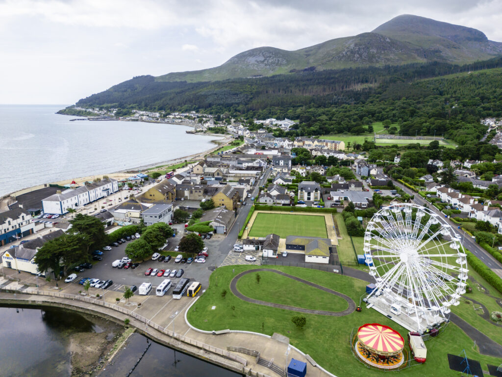 Luftaufnahme von Newcastle in Nordirland mit Strandpromenade, Häusern und den grünen Mourne Mountains im Hintergrund.
