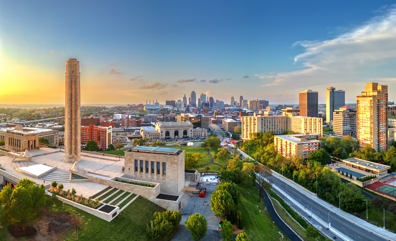 Weitwinkelblick vom Hügel auf die Skyline von Kansas City mit Monument und Bahnhof im Vordergrund.