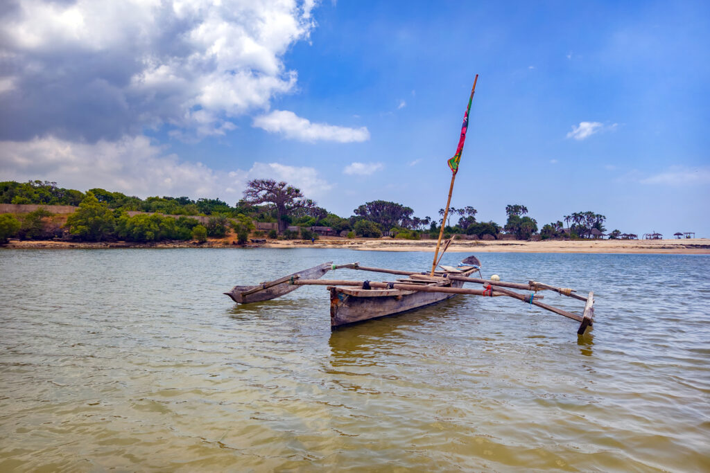 Kleines Auslegerboot treibt vor der Küste von Lamu, Kenia im ruhigen Wasser.
