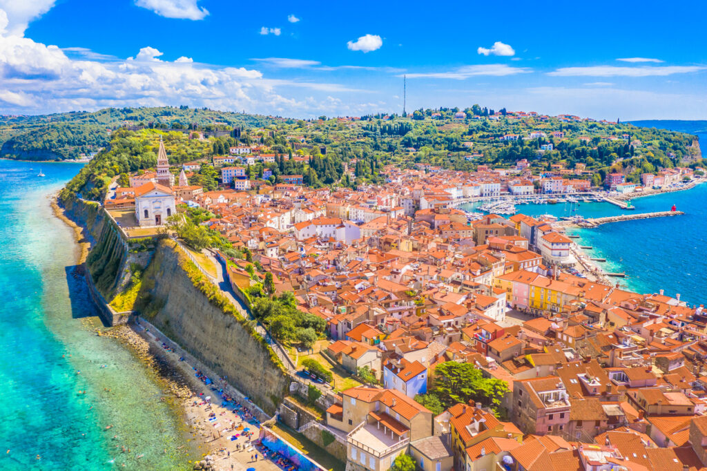 Luftaufnahme der Halbinsel mit der Altstadt von Piran in Slowenien, Stadtmauer und türkisblauem Meer.