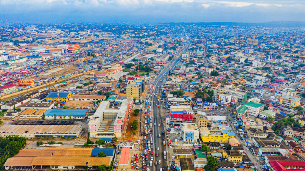 Luftaufnahme von Accra in Ghana mit dichter Bebauung und einer stark befahrenen Hauptstraße in der Mitte.
