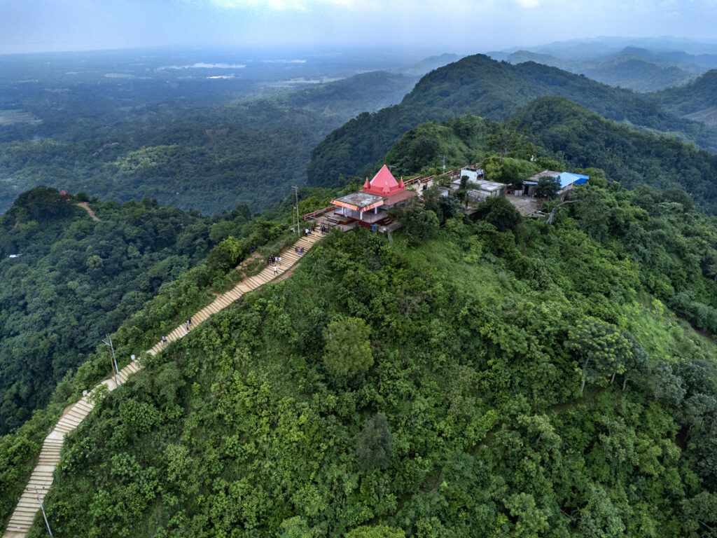 Drohnenaufnahme eines Tempels mit rotem Dach auf einem bewaldeten Hügel in der Nähe von Chittagong / Chattogram.