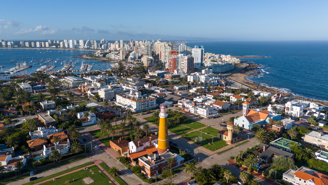 Luftaufnahme mit gelbem Leuchtturm, Wohnvierteln und Hafen von Punta del Este.