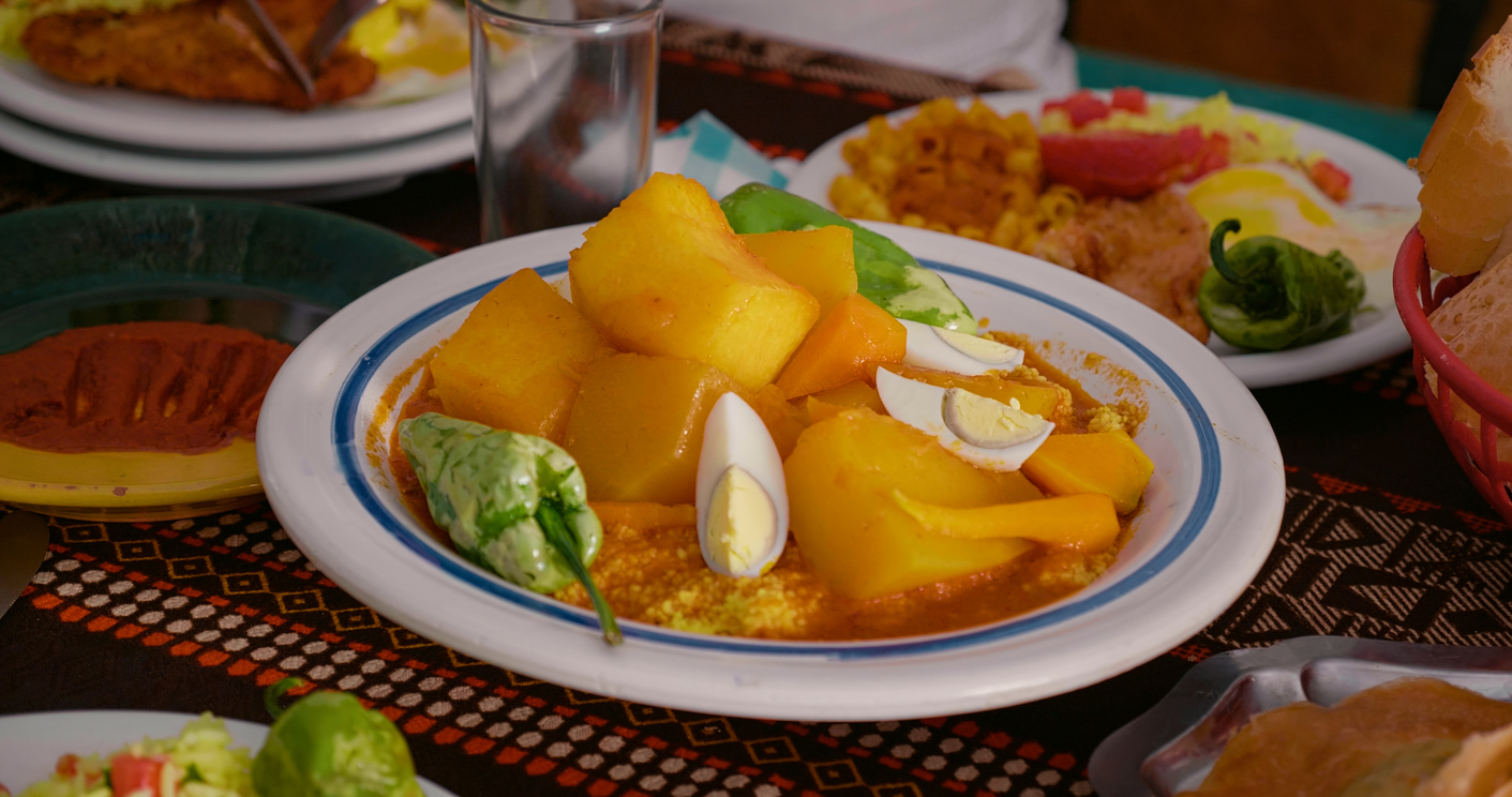 Teller mit tunesischem Couscous und großen Kartoffelstücken, garniert mit Eiern und grüner Paprika.
