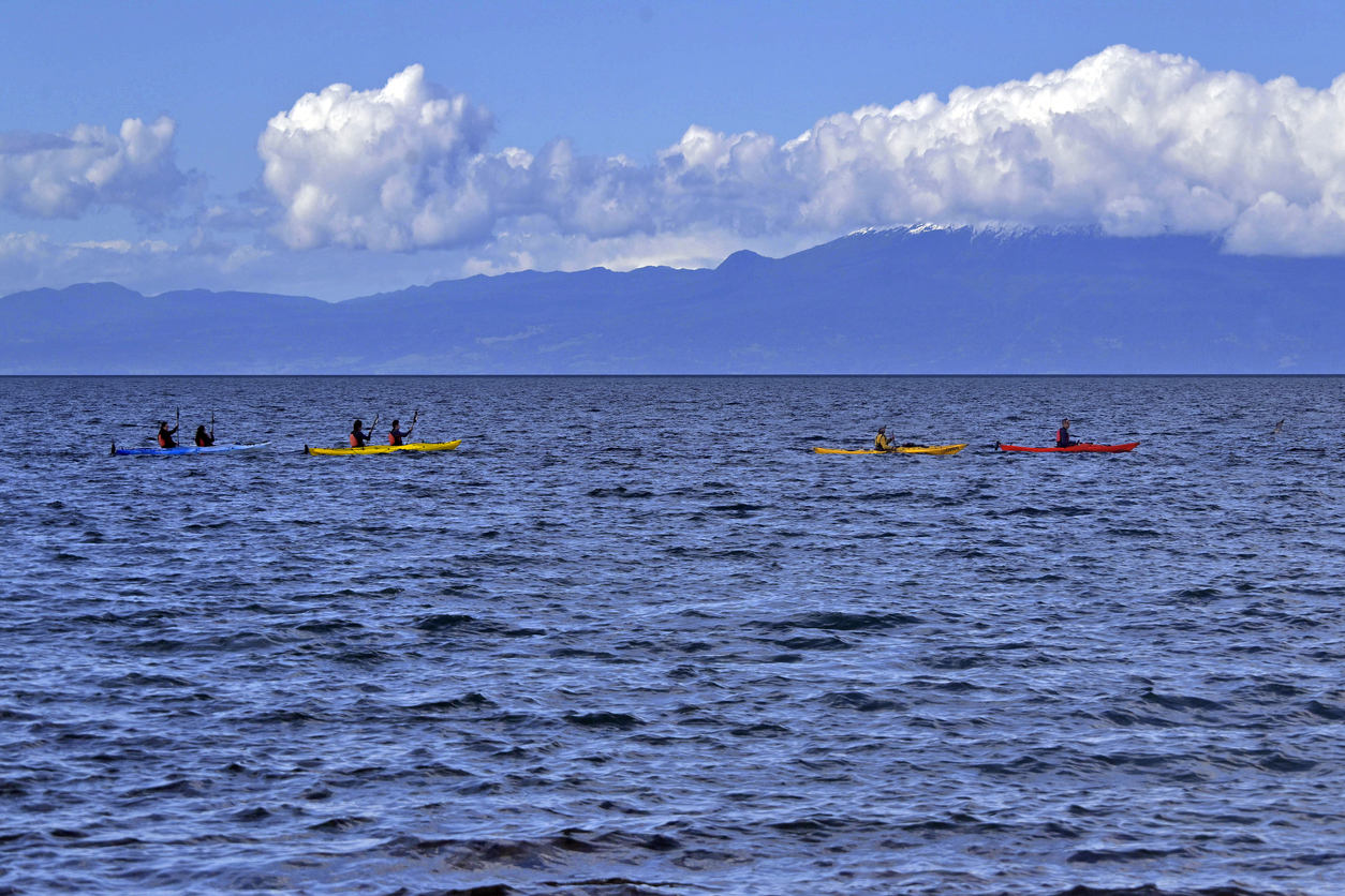 Mehrere Kajaks paddeln auf dem Lago Llanquihue bei Puerto Varas, Chile, vor einer Bergkulisse und großen Wolken.