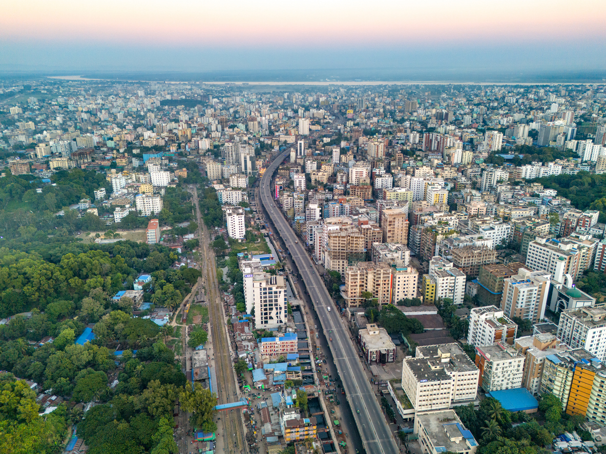 Luftaufnahme von Chittagong / Chattogram mit breiter Schnellstraße, dicht bebauten Wohnvierteln und viel Grün.