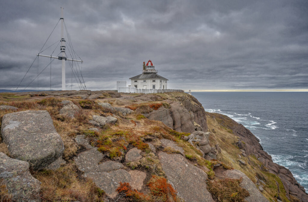 Historischer Leuchtturm von Neufundland steht auf felsigen Klippen über dem stürmischen Atlantik.