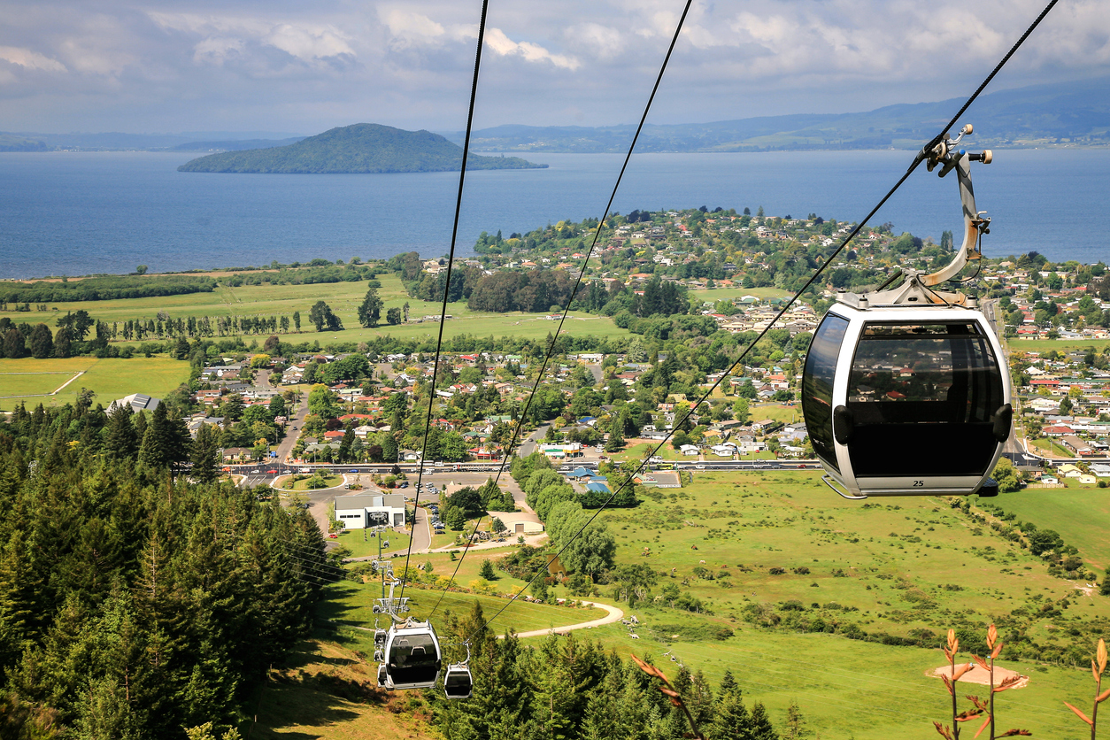 Seilbahngondeln fahren über die grünen Hügel von Rotorua mit Blick auf den Lake Rotorua.