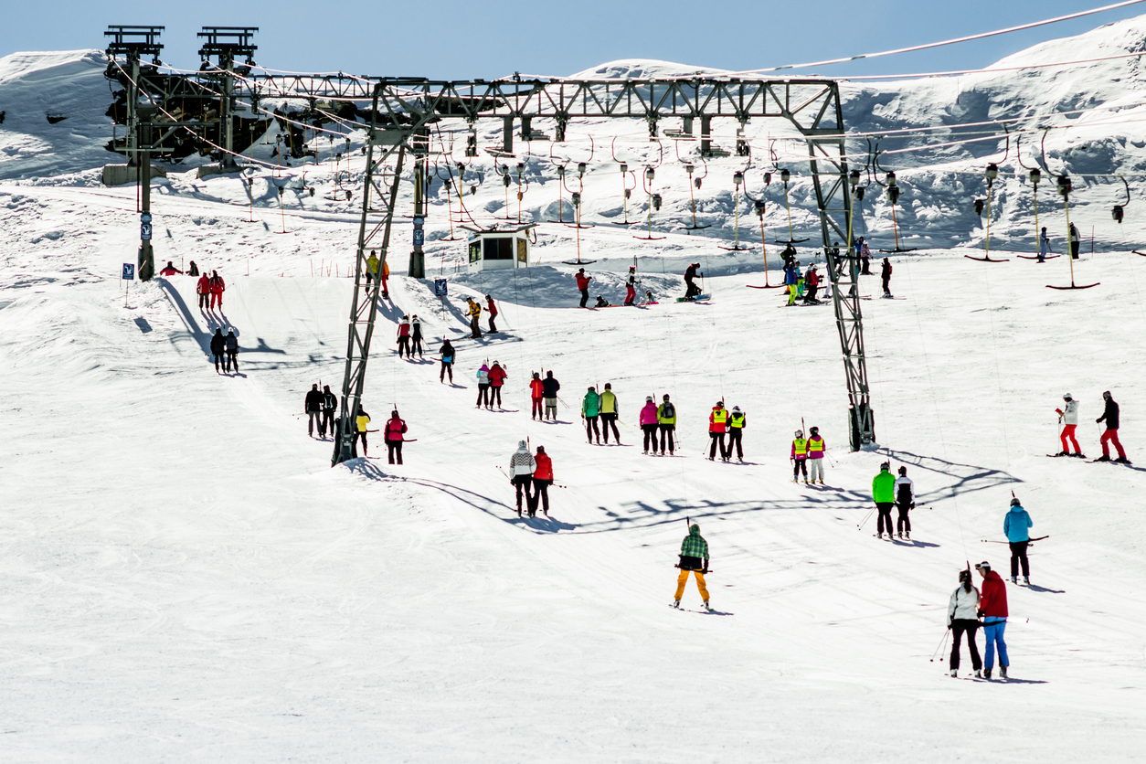 Skifahrer stehen am Schlepplift auf einer verschneiten Piste im Skigebiet Zell am See.