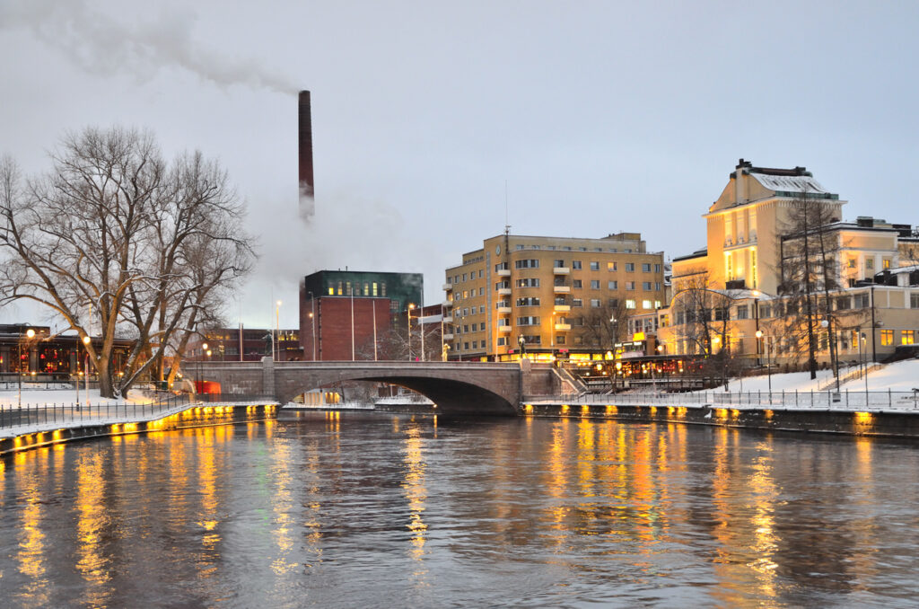 Beleuchtete Uferpromenade und Brücke spiegeln sich im Fluss in Tampere.