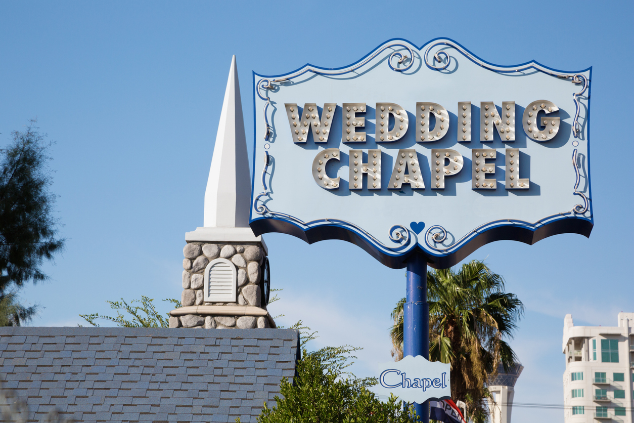 Schild mit der Aufschrift Wedding Chapel in Las Vegas vor blauem Himmel und Palmen.
