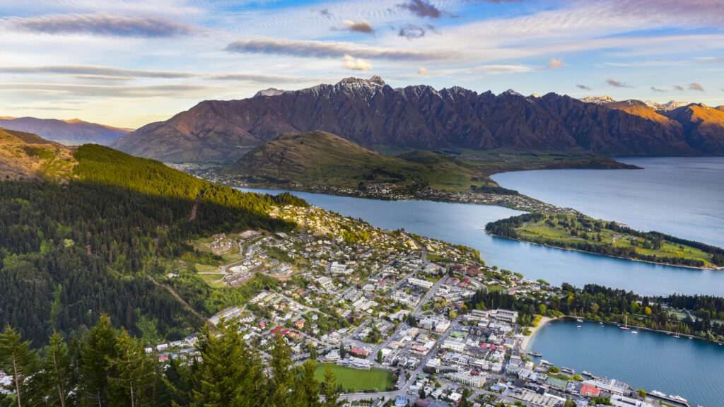 Panorama von Queenstown mit Lake Wakatipu und den Remarkables im Hintergrund bei goldenem Licht.