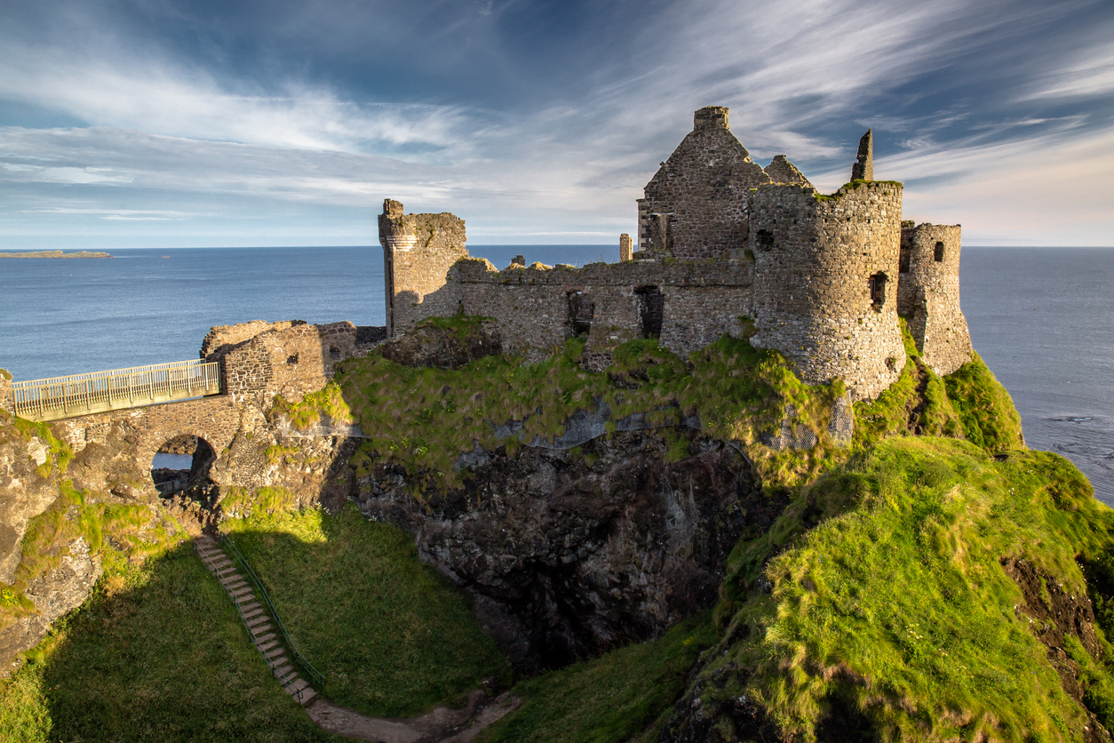 Die Ruinen von Dunluce Castle stehen auf einer grünen Klippe über dem Meer in Nordirland.