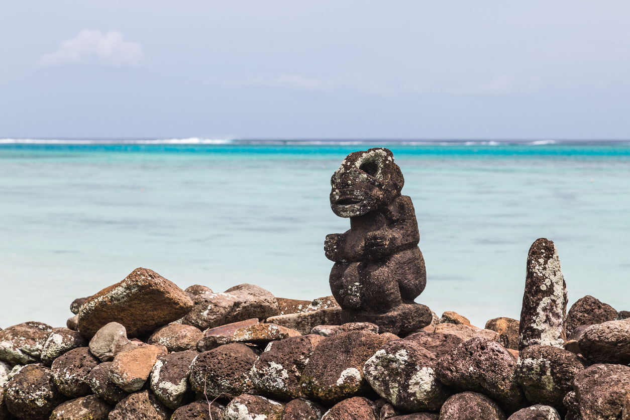 Kleine Steinstatue auf einer Trockenmauer am Meer in Französisch-Polynesien.