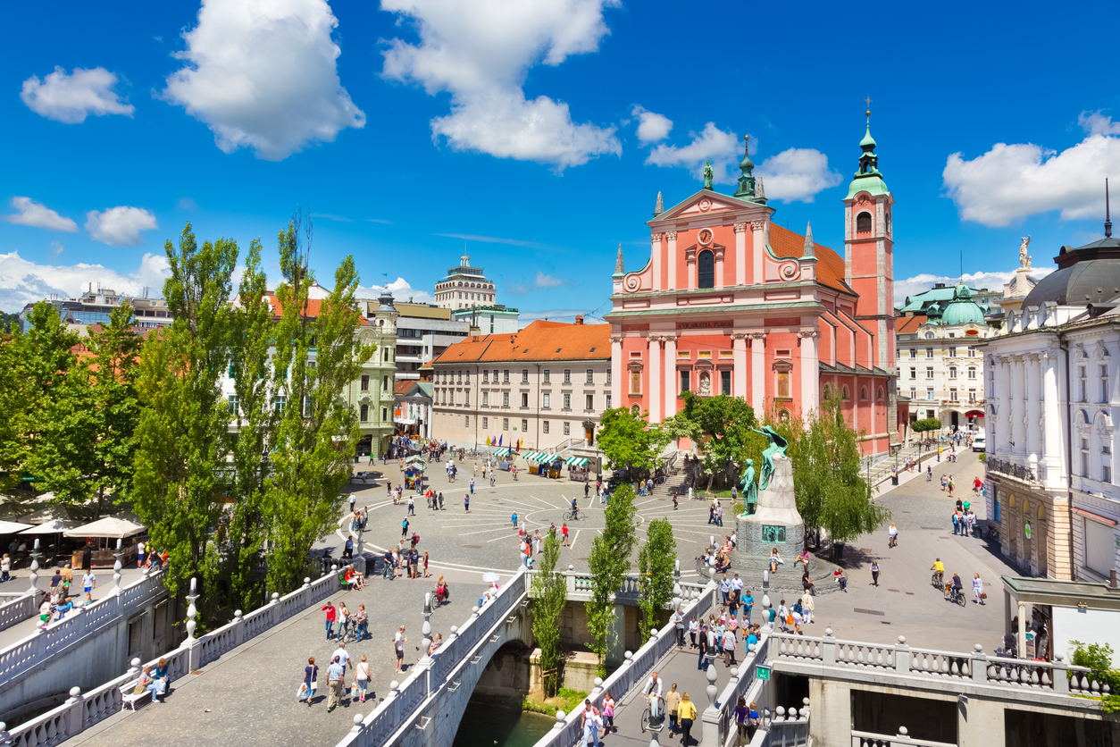 Blick über den Prešerenplatz in Ljubljana mit der rosa Franziskanerkirche und vielen Menschen.