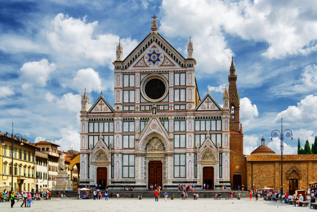 Menschen stehen vor der reich verzierten Kirche Santa Croce in Florenz.