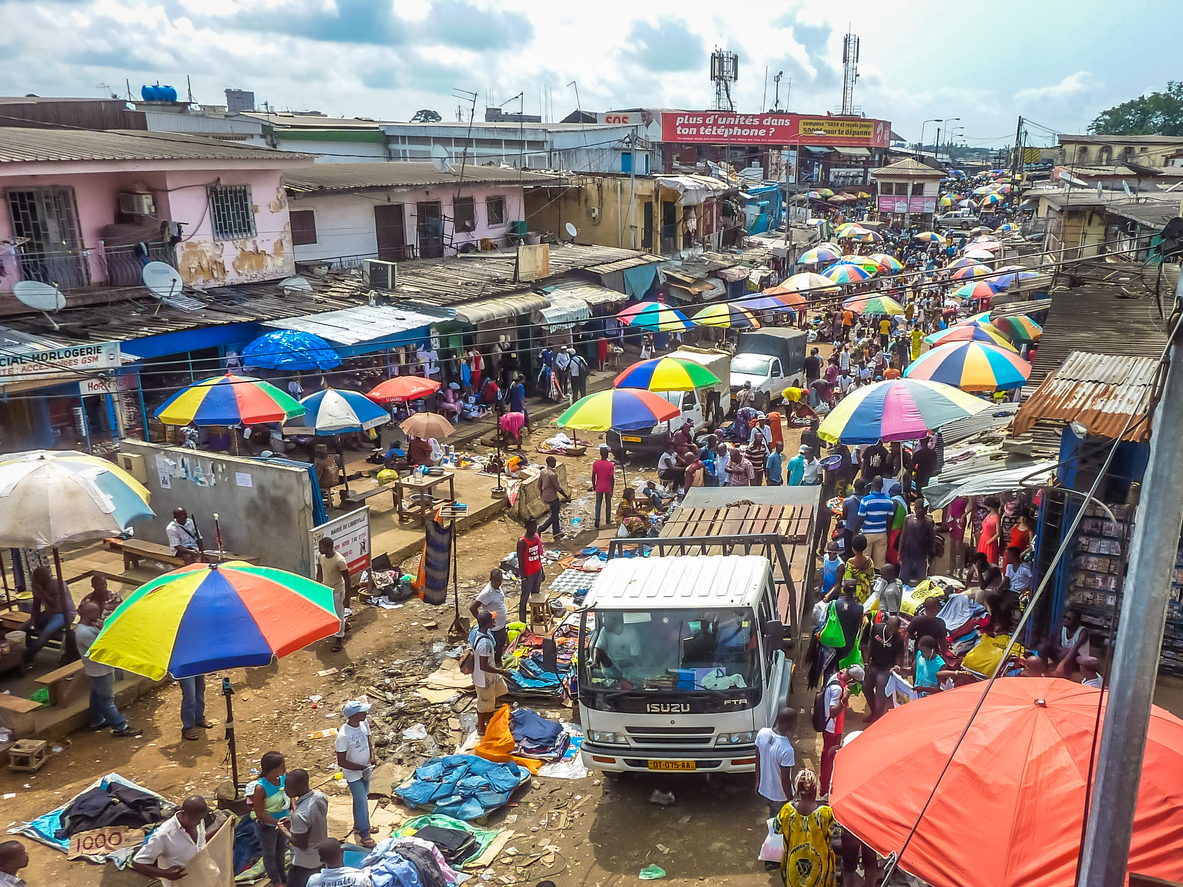 Straßenmarkt in Nairobi mit vielen Menschen, Ständen und bunten Sonnenschirmen.