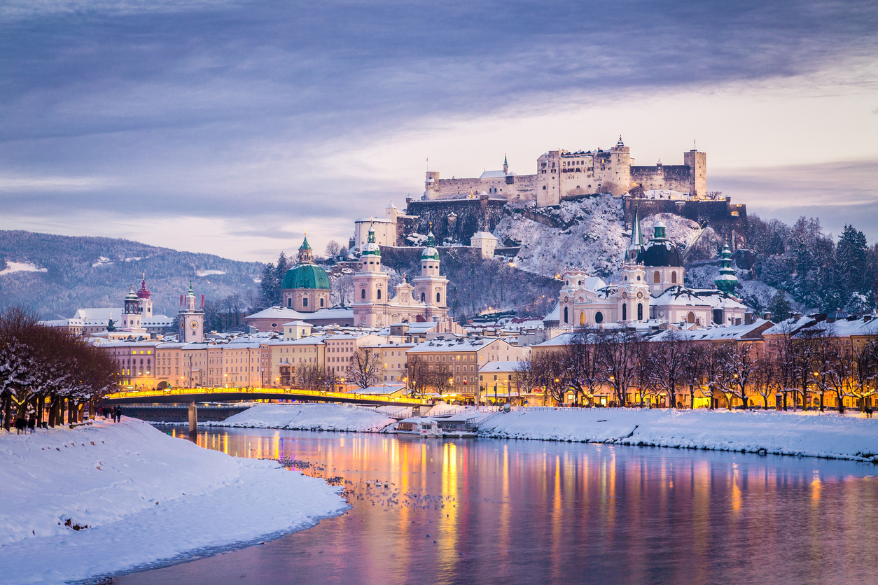 Panorama von Salzburg im Winter mit der Salzach im Vordergrund und der Festung Hohensalzburg über der Altstadt.