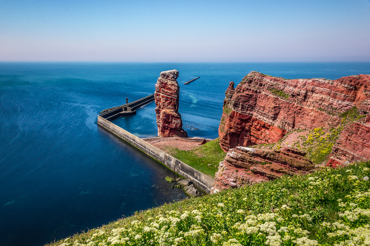 Blick von den roten Klippen auf die Lange Anna und die Hafenmole auf Helgoland.