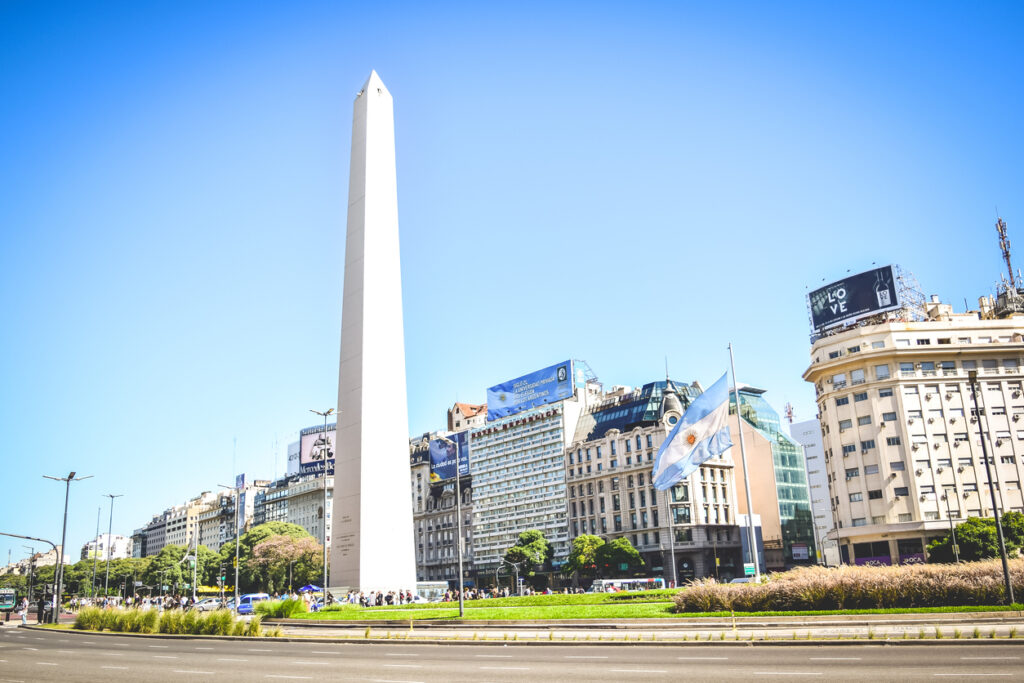 Hoher weißer Obelisk auf einer breiten Straße im Zentrum von Buenos Aires an einem klaren Tag.