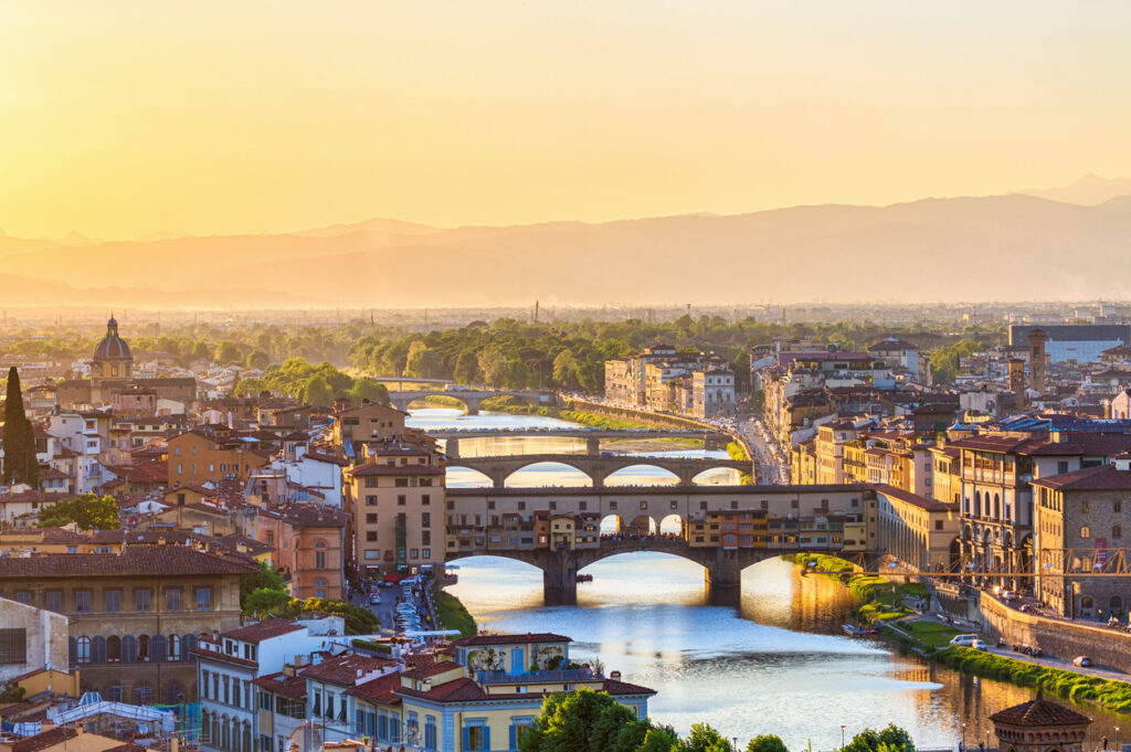 Blick auf den Arno und mehrere Brücken in Florenz bei goldenem Sonnenuntergang.