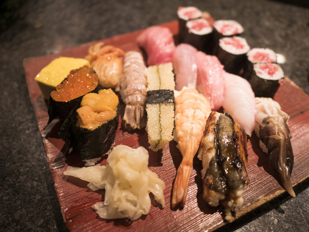 Verschiedene Nigiri und Makis liegen auf einem Holzbrett in einem Sushilokal in Tokio.