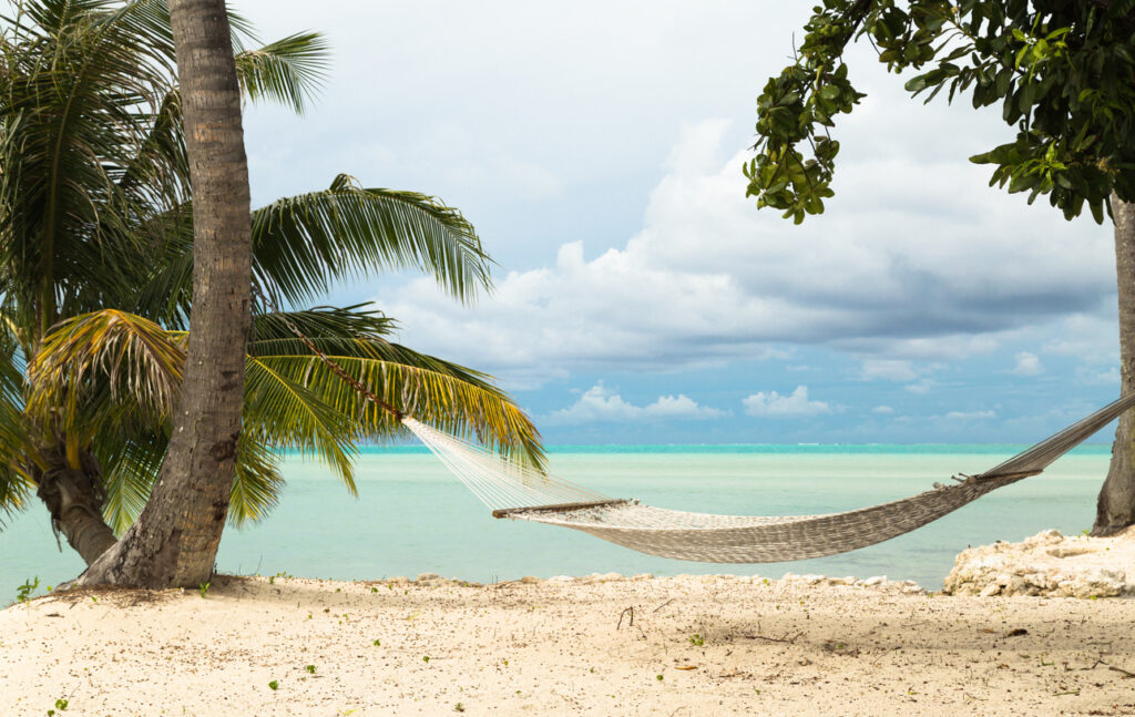 Leere Hängematte zwischen Palmen an einem ruhigen Strand in Französisch-Polynesien.