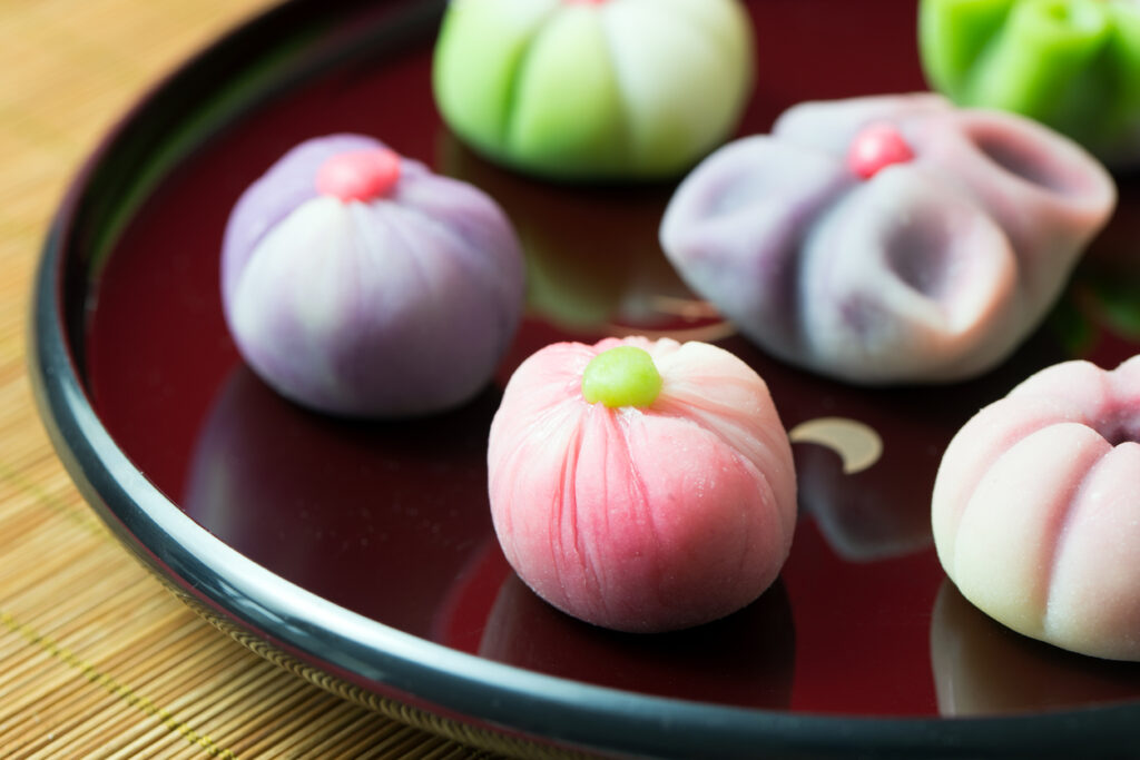 Mehrfarbige japanische Wagashi-Süßigkeiten liegen dekorativ auf einem Lacktablett.