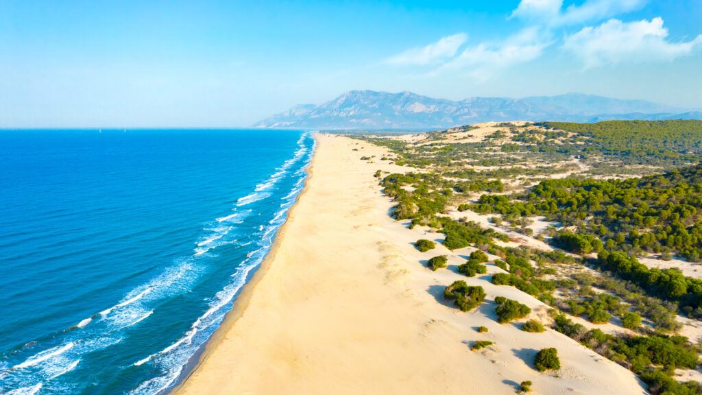 Ein langer Sandstrand mit Dünen zieht sich am Patara Beach entlang der Küste.