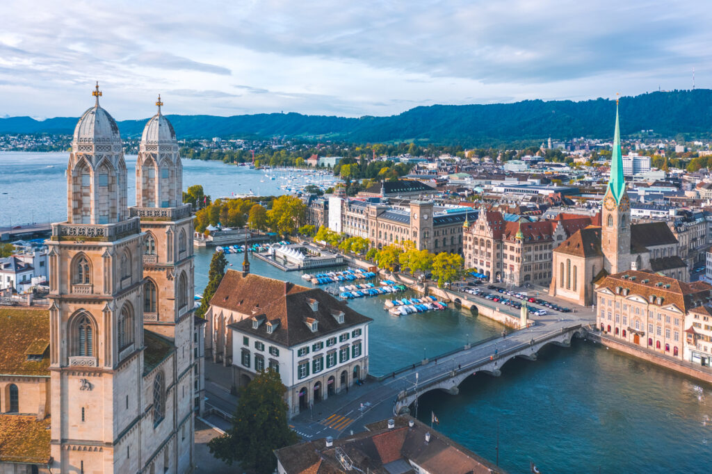 Blick über Zürich mit den Türmen des Grossmünsters, Fluss, Brücke und Altstadt am Wasser.