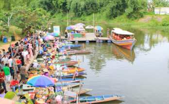 Menschen und Händlerboote drängen sich am Khlong Hae Floating Market, während ein großes Boot am Steg anlegt.