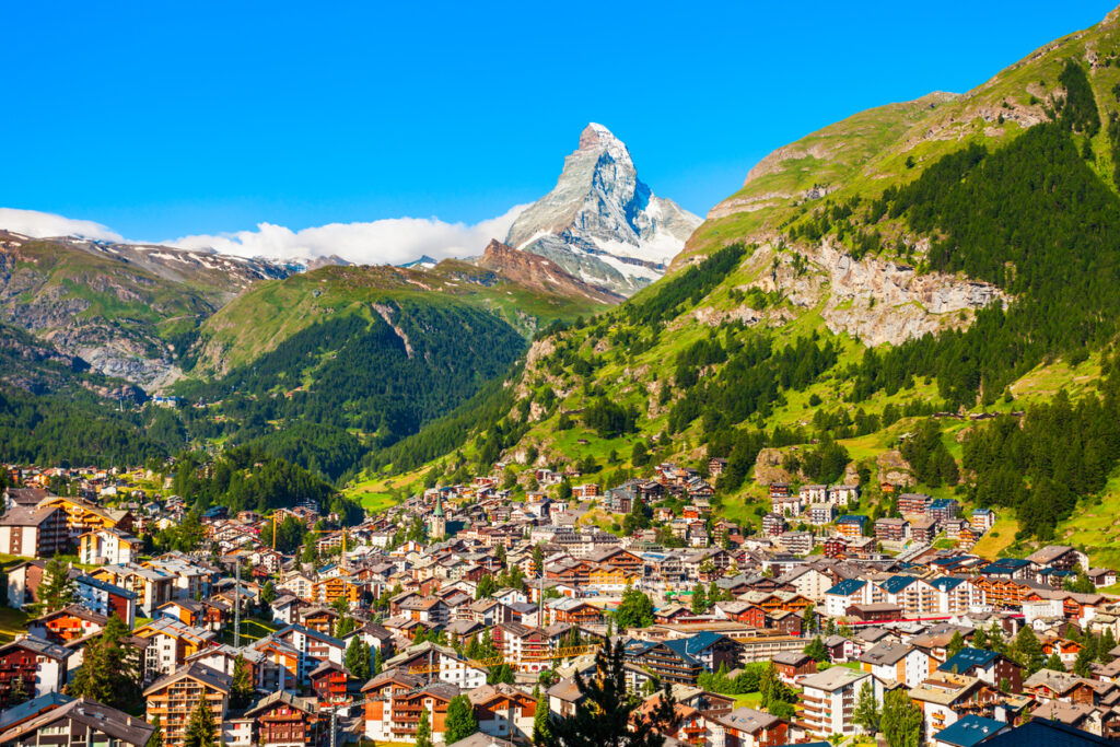 Panorama von Zermatt mit vielen Chalets und dem Matterhorn im Hintergrund bei blauem Himmel.