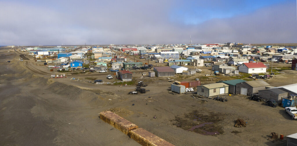 Eine Siedlung mit niedrigen Häusern liegt in Utqiaġvik (Barrow) unter tiefem Himmel.