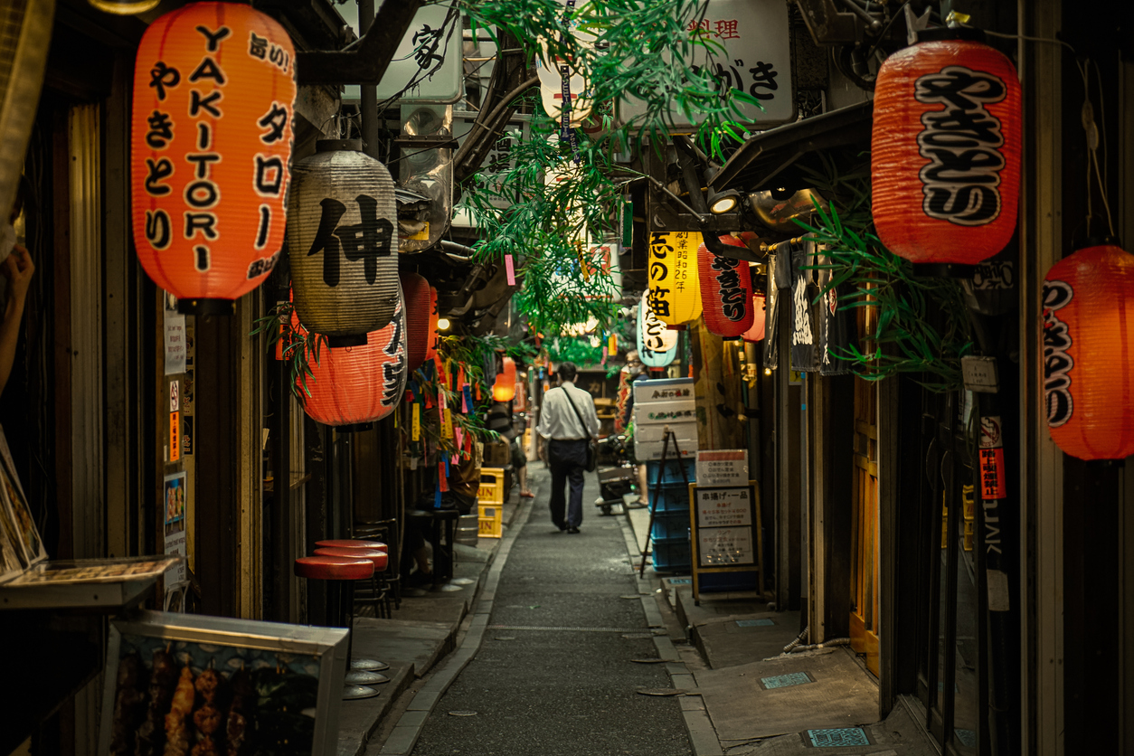 Enge Gasse in Tokyo mit roten Papierlaternen, japanischen Schildern und kleinen Restaurants.