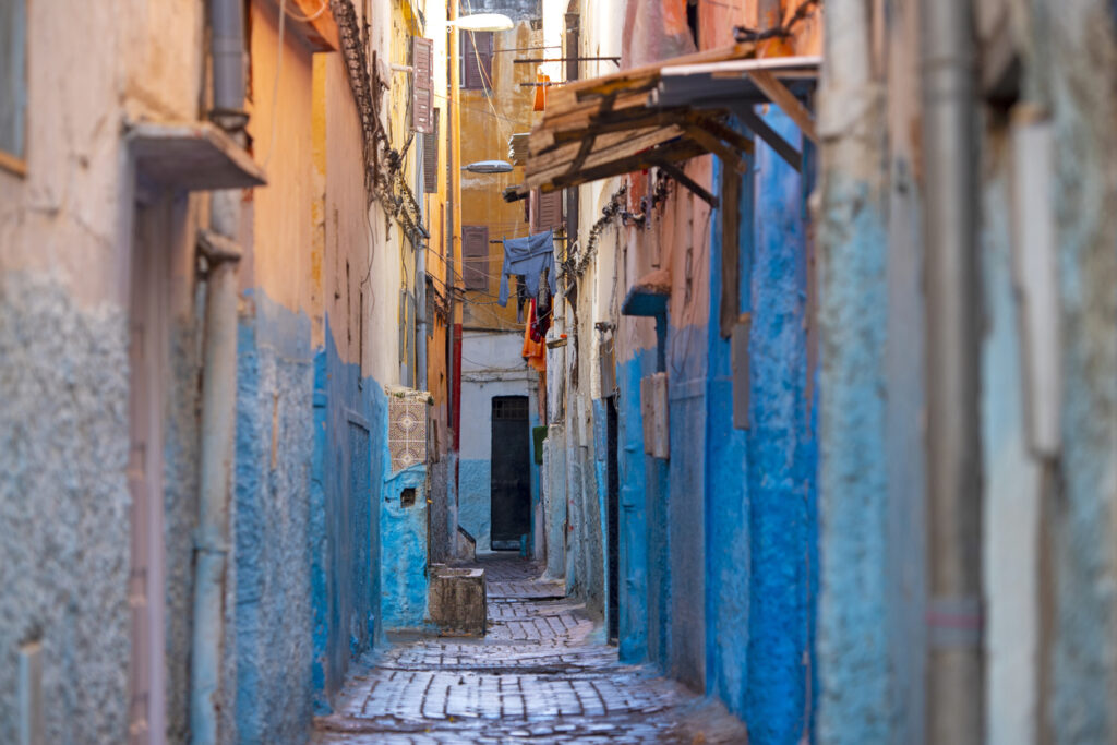 Schmale, blau gestrichene Gasse in der Medina von Casablanca mit Wäscheleinen.